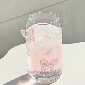 Bicchiere a forma di lattina con farfalle rosa e cubetti di ghiaccio su tavola