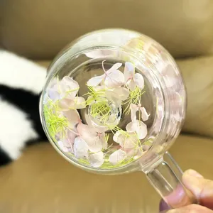 Macro shot of double-walled glass mug with pink flower petals and grass inside layers