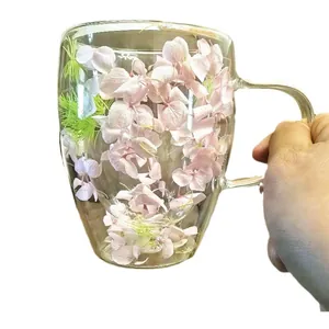 Double-walled glass coffee mug with pink dried flowers and ergonomic handle for breakfast