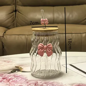 Gedetailleerd zicht op de wolkenglasbeker met roze strik, deksel en rietje