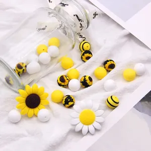 Macro view of sunflower silicone beads and daisy flower charms on white fabric
