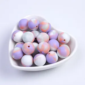 Détail macro de perles en silicone marbrées dans un plat en cœur pour bijoux DIY
