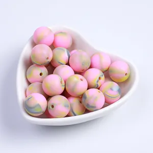 Gros plan de perles en silicone marbré rose dans un bol blanc pour bijoux DIY