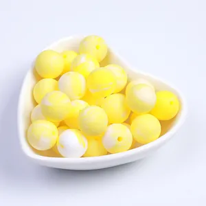 Détail macro de perles en silicone marbré jaune et blanc dans un plateau en forme de cœur