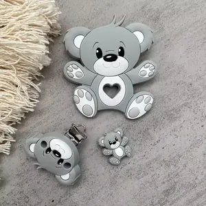 Detail of food-grade silicone baby teether bear set with clip on grey textured background