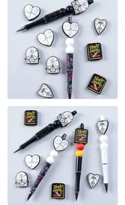 Detalle de bolígrafos góticos con cuentas de silicona de corazón y dijes de libro variados