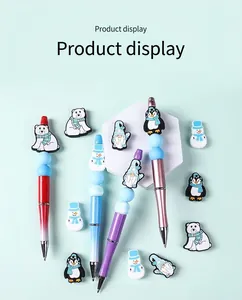 Stifte mit Schneemann- und Pinguin-Silikonperlen auf grünem Hintergrund für DIY-Projekte