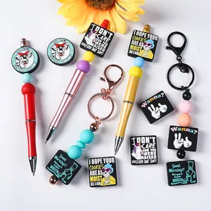 Close-up of DIY silicone beads with metal pens and funny quote charms for accessories