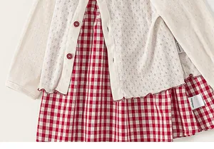Detail of girls white pointelle cardigan with red buttons and red gingham checkered dress