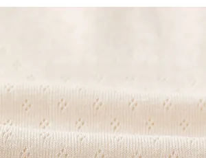 Close-up of soft cream knit fabric with breathable diamond eyelet pattern for kids