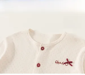 Close-up of knit baby dress with red buttons and embroidered chasing text detail