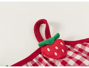 Detail of red gingham baby dress featuring a cute strawberry embroidery and ribbed straps