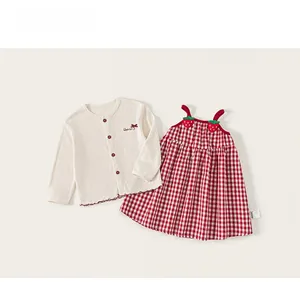 Detail of red strawberry accents and plaid pattern on girl's two-piece dress set