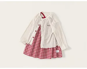 Detail of baby girl's cream pointelle knit cardigan and red gingham dress with embroidery