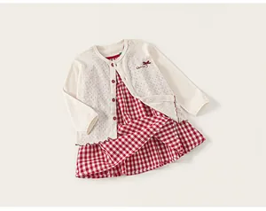 Detailed view of girls red plaid dress and cream hollow knit cardigan set with embroidery