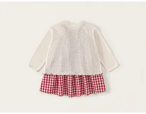 Detail of baby girl dress showing knitted hollow pattern and red checkered skirt