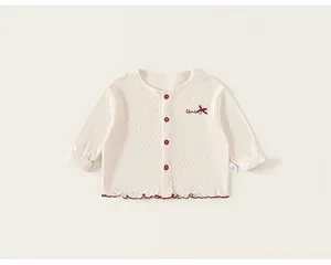 Close-up of cream knit baby cardigan with hollow mesh texture and red wave hem