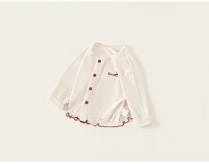 Close-up of baby cardigan featuring breathable eyelet texture and red ruffled edges