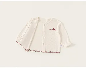 Detail of baby knit cardigan with diamond hollow texture and bow embroidery