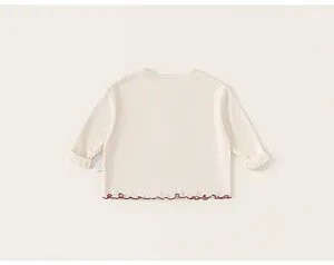 Detailed view of cream pointelle knit fabric with red scalloped hem and side label