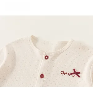 Detail of baby pointelle knit top with red buttons and embroidered chasing bow detail