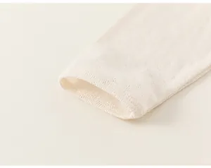 Detail of cream pointelle cotton sleeve with delicate hollow knit patterns and ribbed cuffs