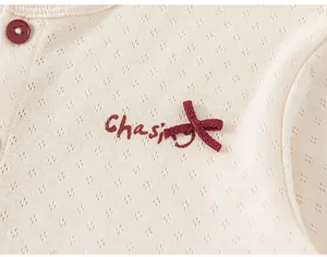 Close-up of pointelle knit fabric with a red bow and button on the girls strawberry dress