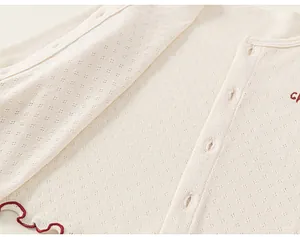 Detail of baby cream knit cardigan with strawberry red trim and embroidery