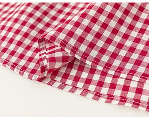 Close-up of red and white gingham cotton fabric with detailed stitching on the garment hem