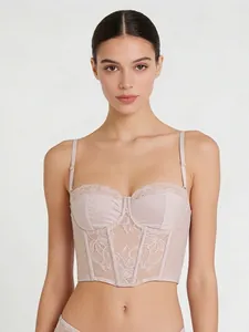 Detailed close-up of light pink corset bra featuring floral lace and boning structure