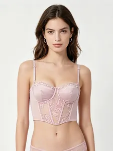 Detailed close-up of light pink lace bustier bra with floral embroidery and satin texture