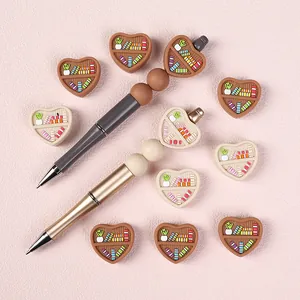 Perles en silicone en forme de cœur et stylos sur un fond à texture douce