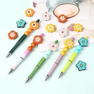 Set of DIY colorful floral silicone bead pens and matching craft accessories on blue background