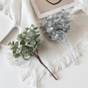 Detail of frosted artificial eucalyptus leaves and realistic stems on white fabric