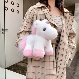 Plüsch Einhorn Anhänger in Weiß mit rosa Details, von einem Model zur Ansicht gehalten