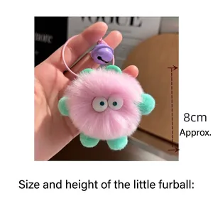 Detail of pink fluffy soot sprite keychain with mint green ears and purple bell accessory