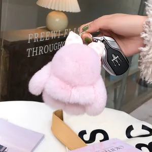 Pink plush rabbit keychain with polka dot bow attached to car key on stylish background