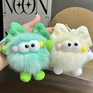 Primer plano de llaveros de peluche en verde menta y crema con ojos grandes y lazos