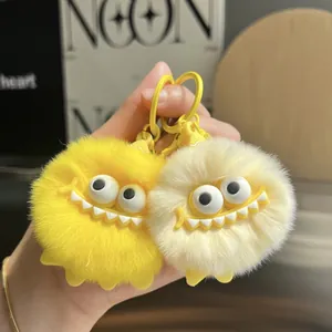 Plush faux fur monster keychains in yellow and beige with large eyes and plastic clips
