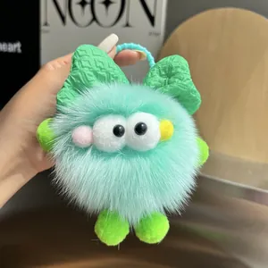 Detalle de un monstruo de peluche verde menta con lazo verde y cadena de cuentas