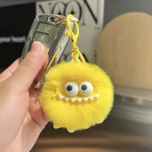 Close-up of bright yellow plush monster keychain with fuzzy texture and cute white teeth