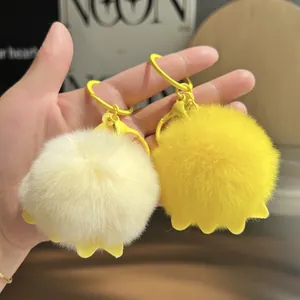 Detail of plush fluffy keychains in beige and yellow with soft rubber accents