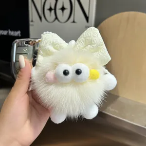 Detalle de llavero de peluche blanco con ojos grandes y cinta en una llave de coche