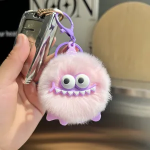 Pink plush monster keychain with purple silicone accents shown in use on a car key