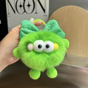 Detalle de llavero de piel sintética verde con ojos grandes y lazo para bolsos