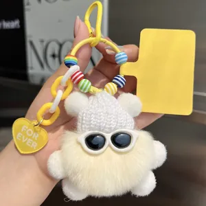 Detail of white plush bear charm with mini knit hat, sunglasses, and yellow chain