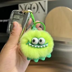 Close-up of fluffy green monster keychain with big eyes and white teeth on a car key