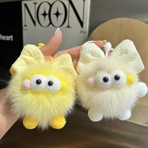 Detalle de llaveros de peluche con ojos grandes y lazos en color amarillo y blanco