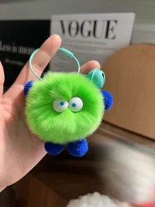 Close-up of fluffy neon green plush monster keychain with blue limbs and a blue bell charm