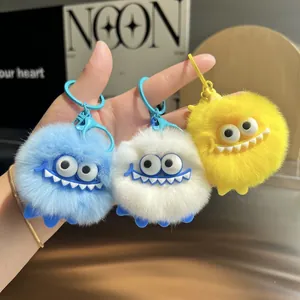 Plush monster keychains in blue, white, and yellow with big eyes and fuzzy texture